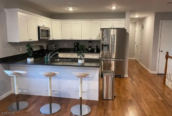 a kitchen with stainless steel appliances granite countertop a stove a refrigerator a sink a microwave and wooden floors