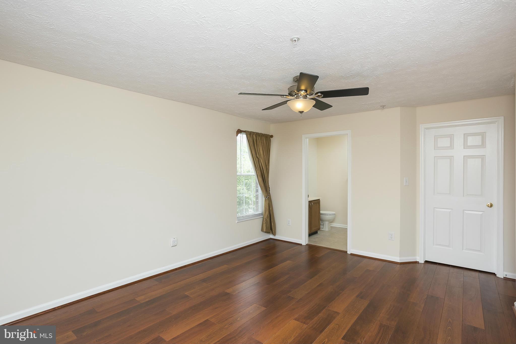 693 Winding Stream Way, Unit 201 Odenton, MD 21113 - Photo 12 of 28 a view of an empty room with wooden floor and a ceiling fan