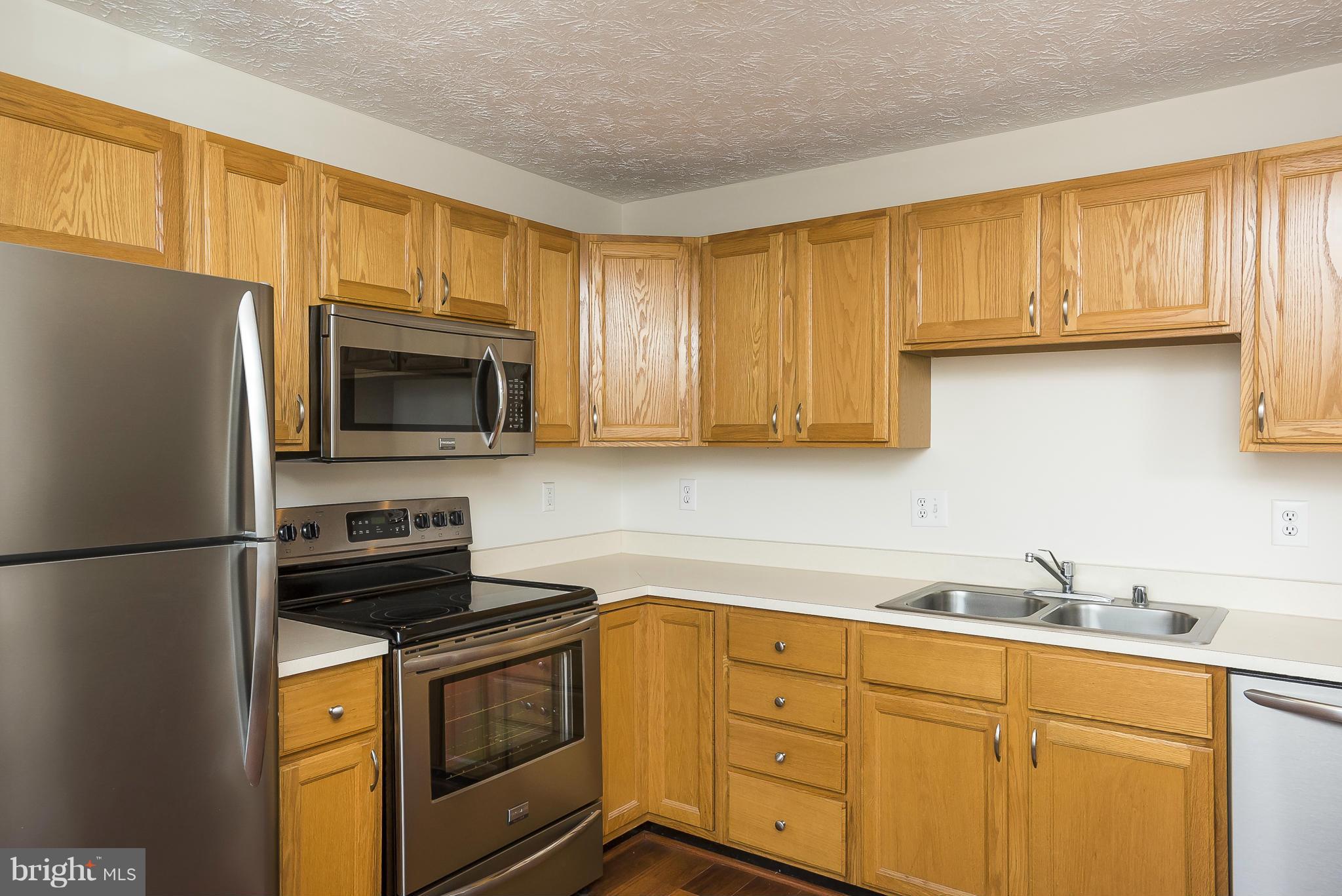 693 Winding Stream Way, Unit 201 Odenton, MD 21113 - Photo 7 of 28 a kitchen with stainless steel appliances granite countertop a refrigerator stove top oven a sink and dishwasher