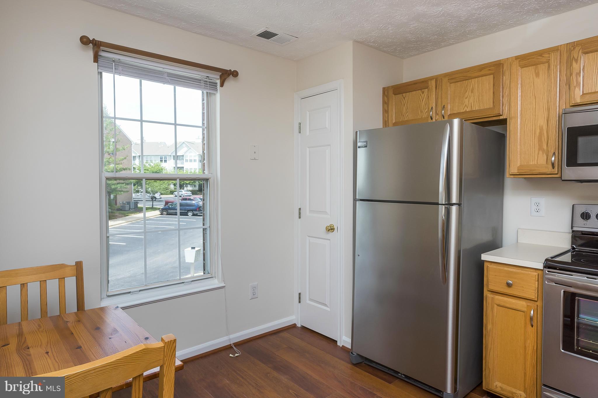 693 Winding Stream Way, Unit 201 Odenton, MD 21113 - Photo 9 of 28 a refrigerator freezer sitting in a kitchen with stainless steel appliances wooden floor