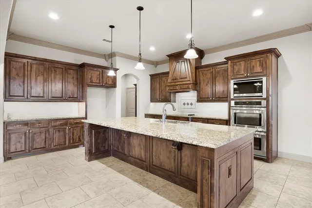 a kitchen with stainless steel appliances granite countertop a sink a stove and a wooden cabinets