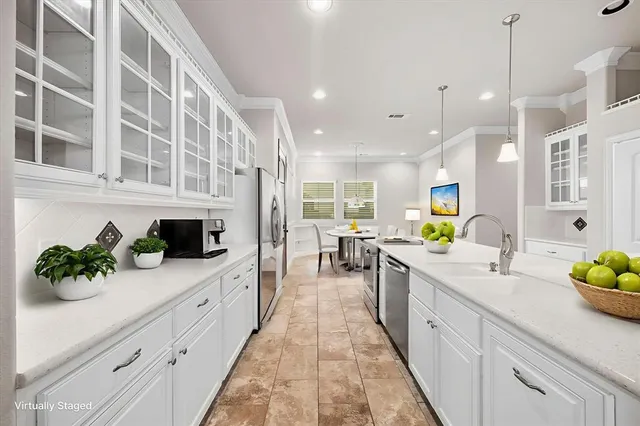 a large white kitchen with stainless steel appliances lots of counter space and a sink