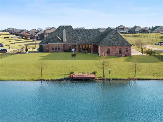 a front view of a house with a garden and lake view