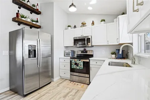 a kitchen with stainless steel appliances kitchen island a refrigerator sink and cabinets