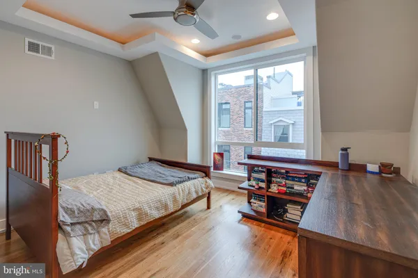 a bedroom with a bed and a large window with wooden floor