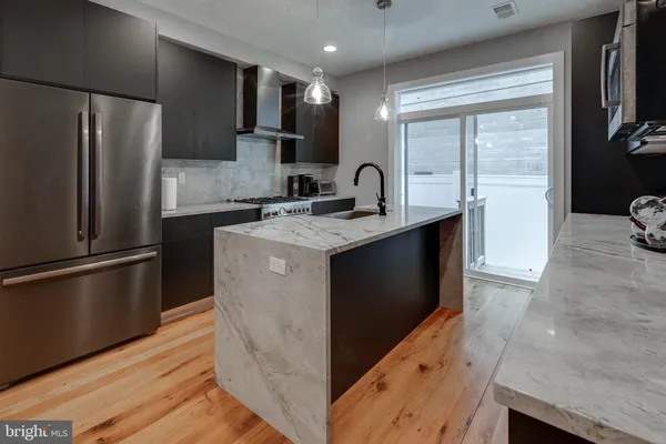 a kitchen with stainless steel appliances granite countertop a refrigerator a sink and a stove