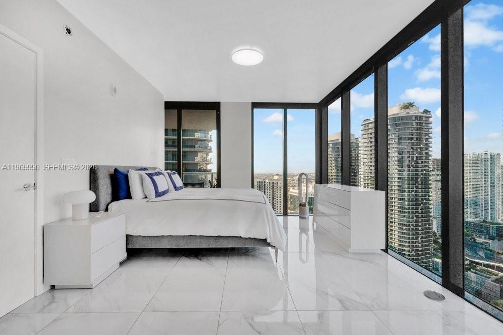 1010 Brickell Avenue, Unit 4011 Miami, FL 33131 - Photo 10 of 32 a large white bed sitting in a room next to a large window