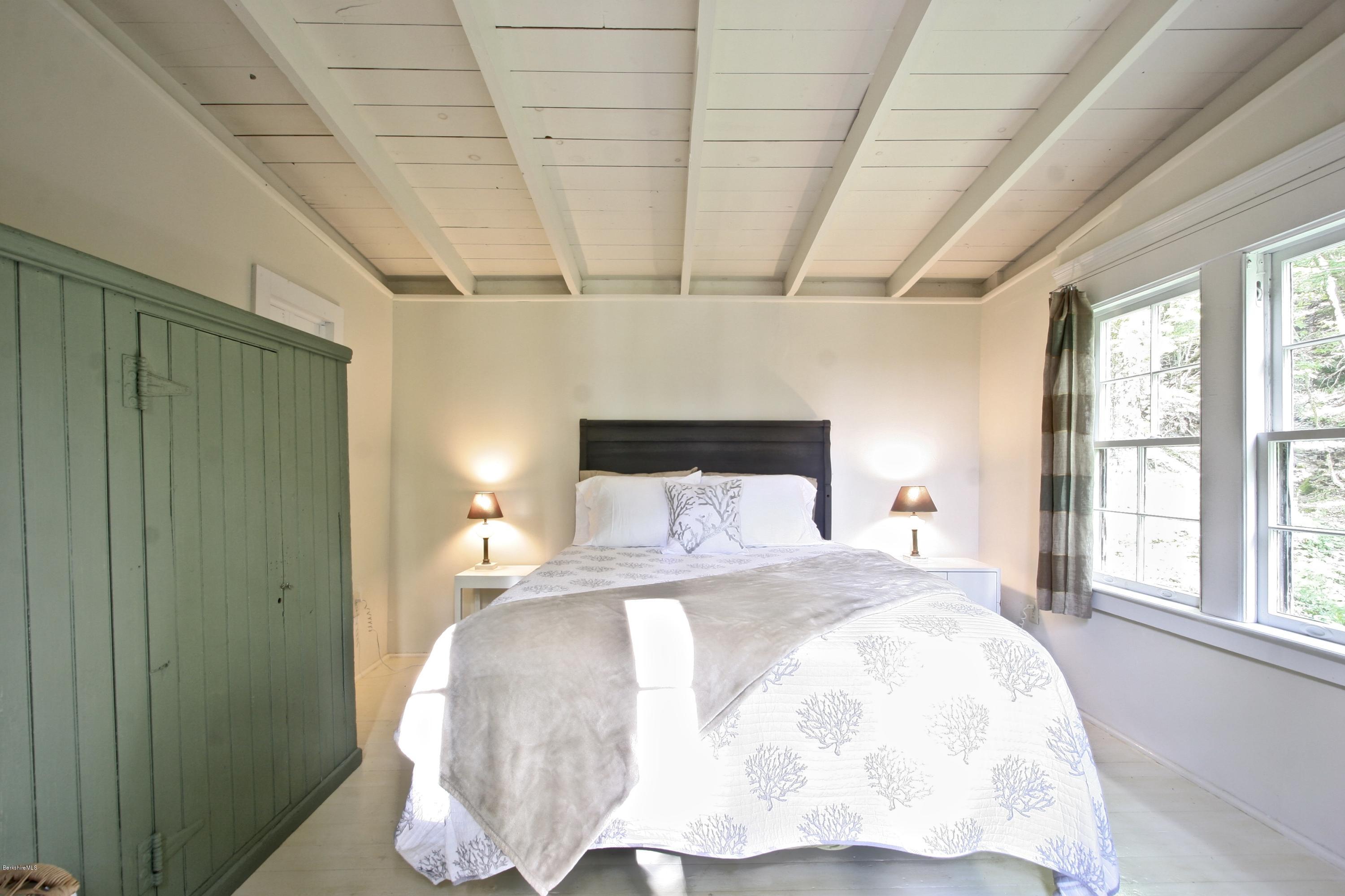 22 Mahkeenac Road Stockbridge, MA 01262 - Photo 16 of 24 a large bed sitting in a bedroom next to a window and chandelier