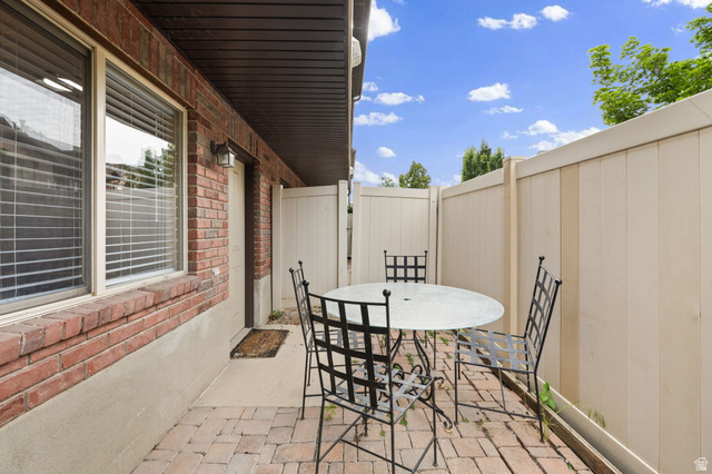 204 Lyman Lane Bountiful, UT 84010 - Photo 25 of 28 Private brick paver patio area featuring a red brick exterior, a secure privacy fence, and an exterior wall light fixture