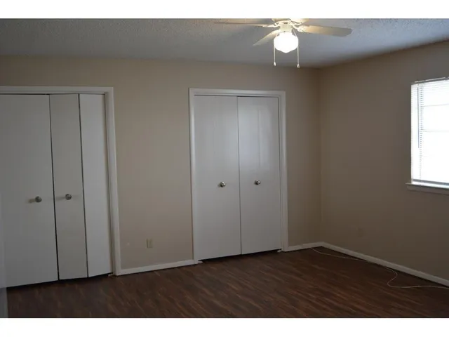 a view of an empty room with wooden floor and window