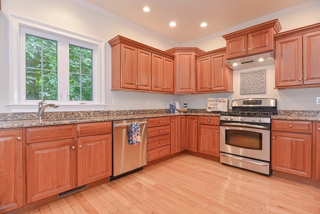 159 Prospect Street, Unit 7 Acton, MA 01720 - Photo 6 of 31 a kitchen with granite countertop wooden floors and white appliances