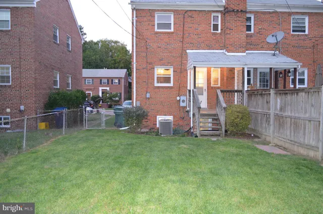 a view of a brick house with a yard and table and chairs under an umbrella