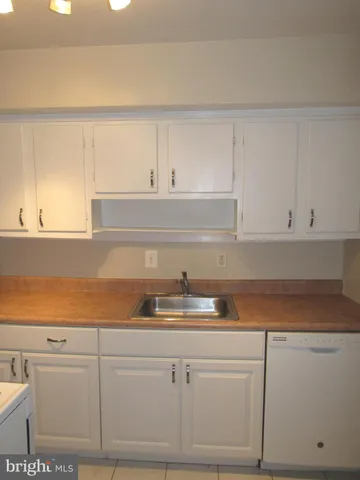 a kitchen with white cabinets and sink