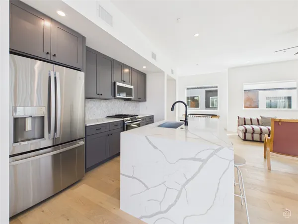 a kitchen with stainless steel appliances kitchen island a refrigerator sink and cabinets