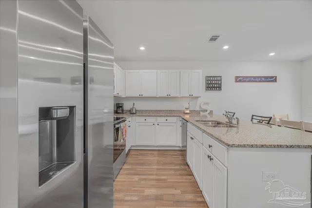 a kitchen with granite countertop white cabinets sink and stainless steel appliances