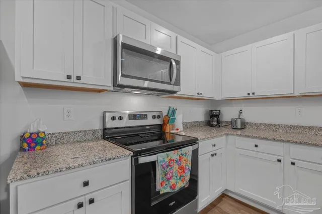 a kitchen with stainless steel appliances granite countertop a stove a refrigerator a sink a dining table and chairs with wooden floor