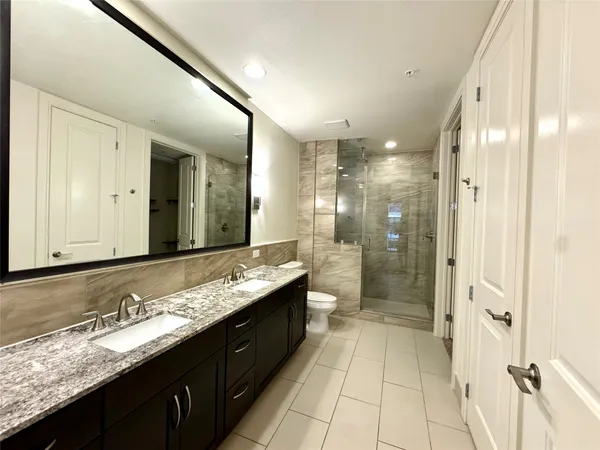 a bathroom with a granite countertop sink mirror and a shower