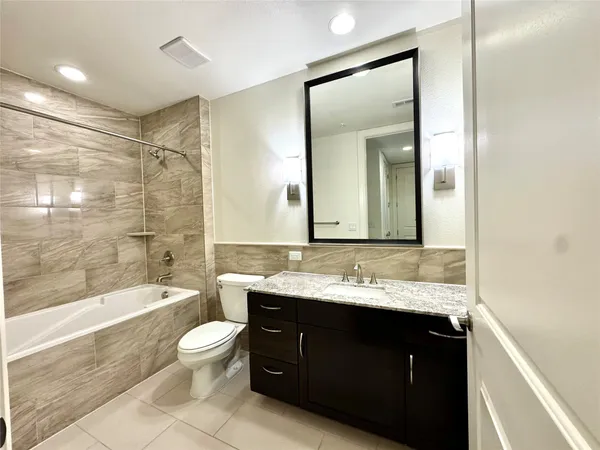 a bathroom with a granite countertop sink toilet mirror and bathtub