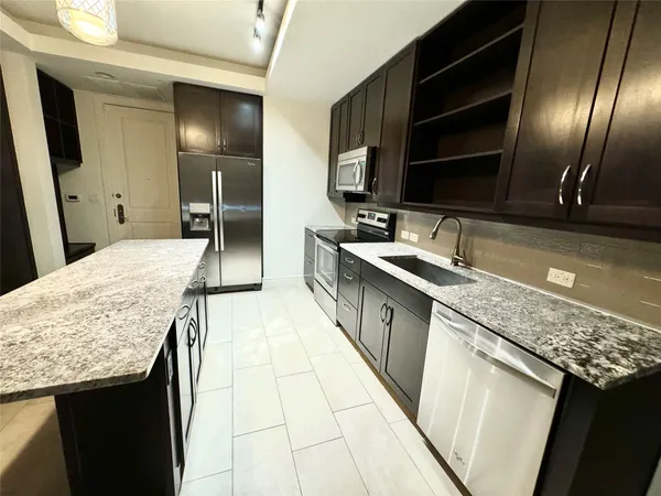 a large kitchen with granite countertop a sink and cabinets