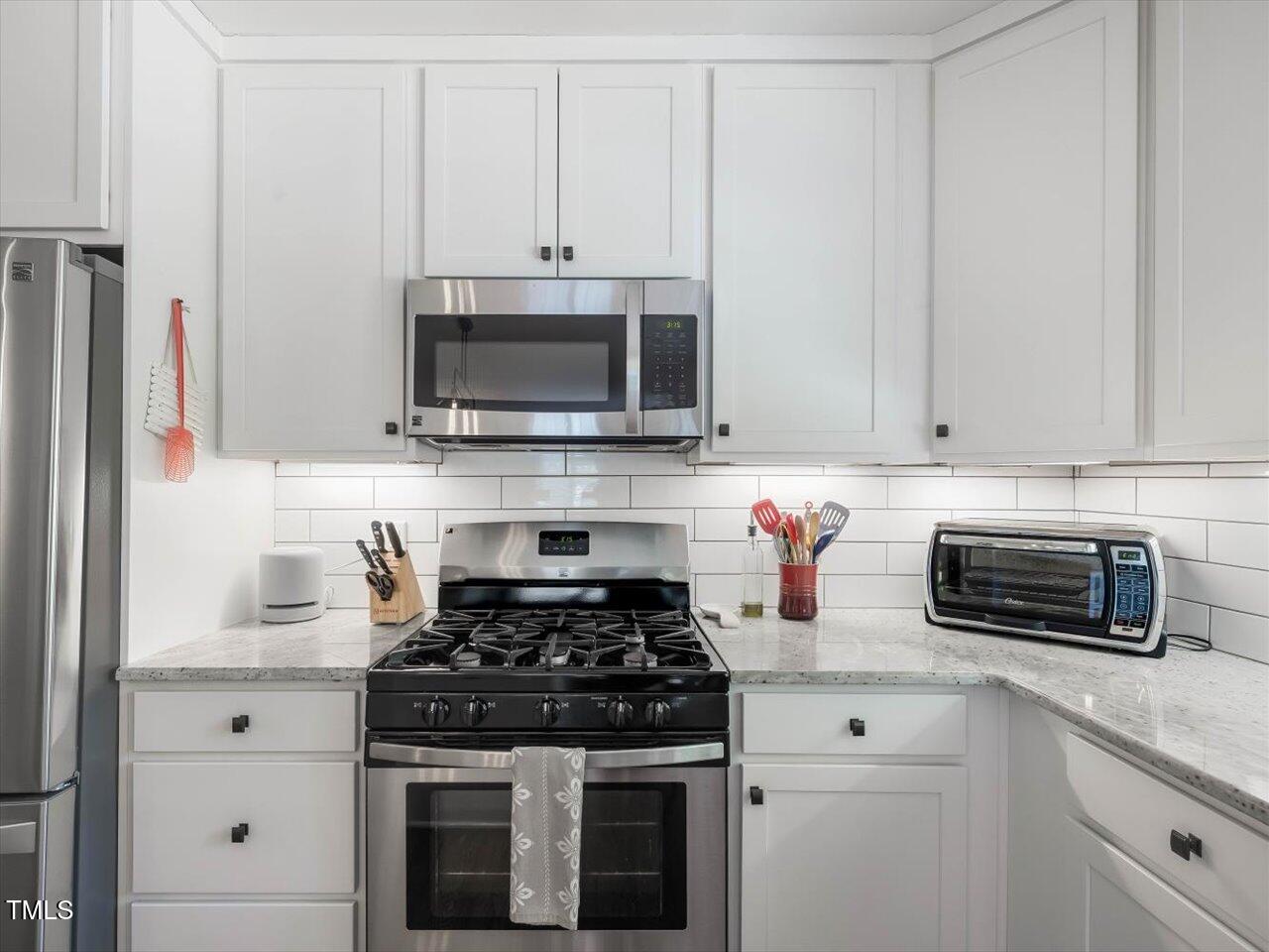 1310 Carolina Pines Avenue Raleigh, NC 27603 - Photo 20 of 53 a kitchen with stainless steel appliances granite countertop white cabinets a stove a microwave and a refrigerator