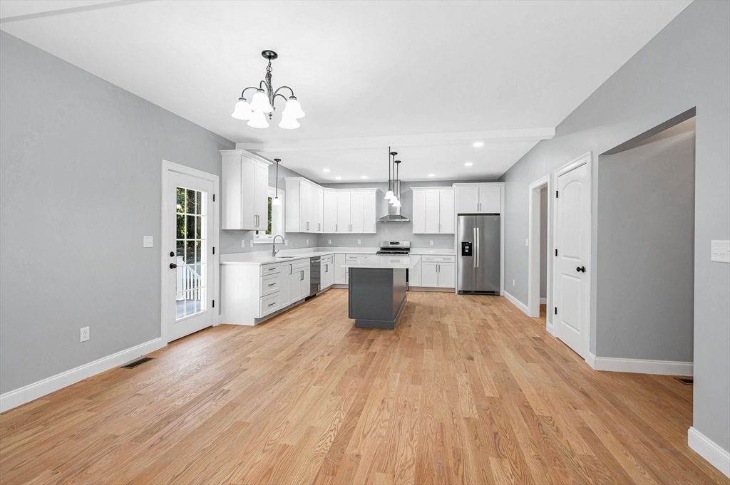 17 Norris Road Tyngsborough, MA 01879 - Photo 9 of 42 a large kitchen with kitchen island a stove a sink dishwasher a refrigerator and white cabinets with wooden floor