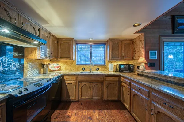 a living room with stainless steel appliances granite countertop a refrigerator and a sink