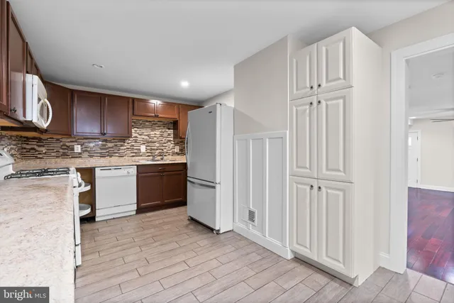 a kitchen with granite countertop wooden cabinets a sink and dishwasher a stove with wooden floor