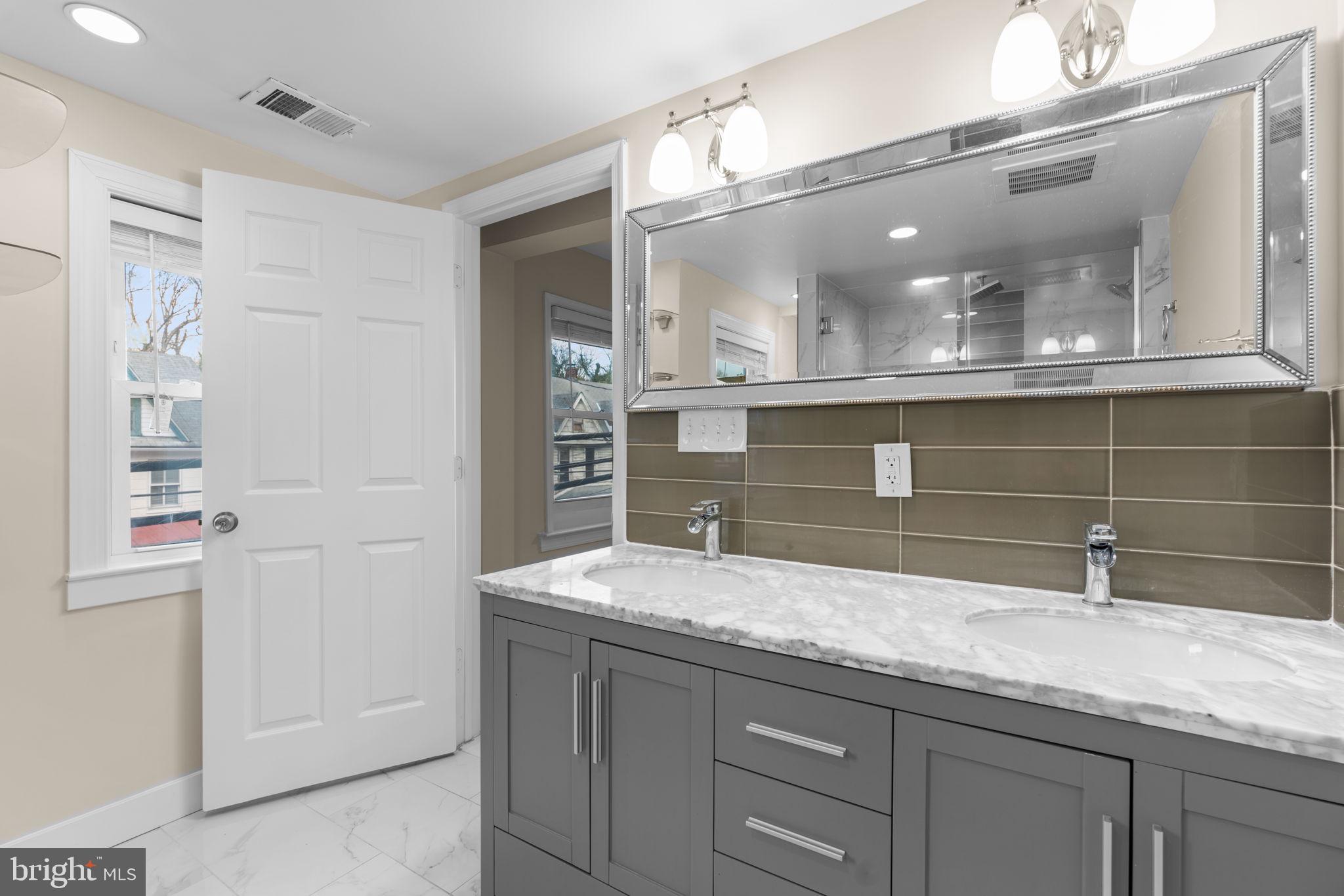 8483 Frederick Road Ellicott City, MD 21043 - Photo 23 of 44 a bathroom with a granite countertop sink a mirror and a shower