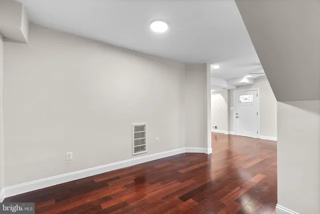an empty room with wooden floor and ceiling fan