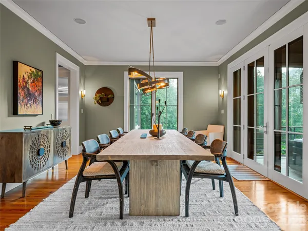 a kitchen with stainless steel appliances granite countertop a refrigerator a sink dishwasher a stove and a dining table with wooden floor