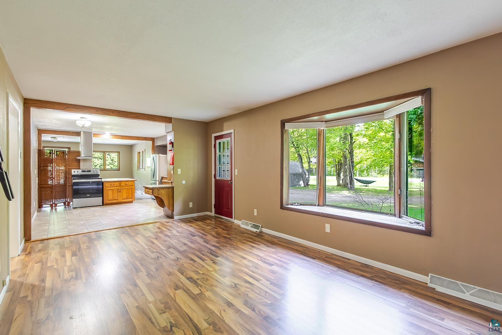7045 Morris Thomas Road Cloquet, MN 55720 - Photo 10 of 28 Spacious interior featuring wood-finish flooring, a large bay window, and a red entry door