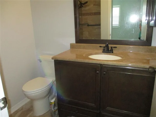 a bathroom with a granite countertop toilet sink and mirror