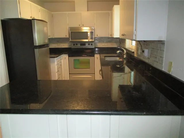 a kitchen with stainless steel appliances granite countertop a refrigerator a stove and a sink