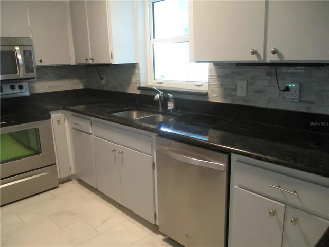 a kitchen with granite countertop white cabinets and white appliances