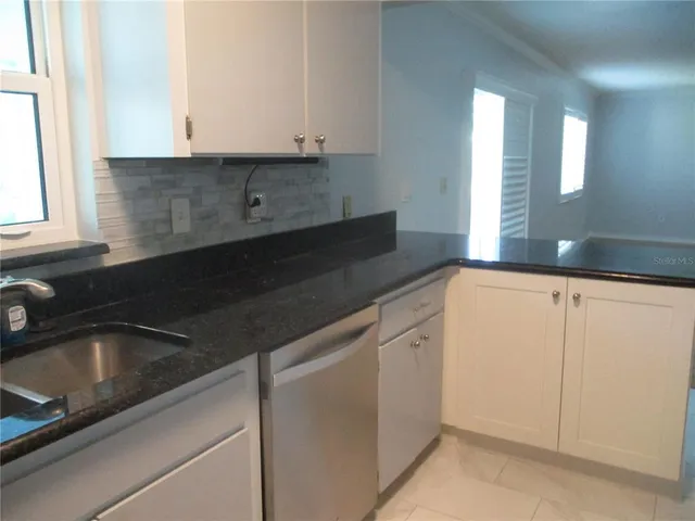 a kitchen with granite countertop white cabinets and sink