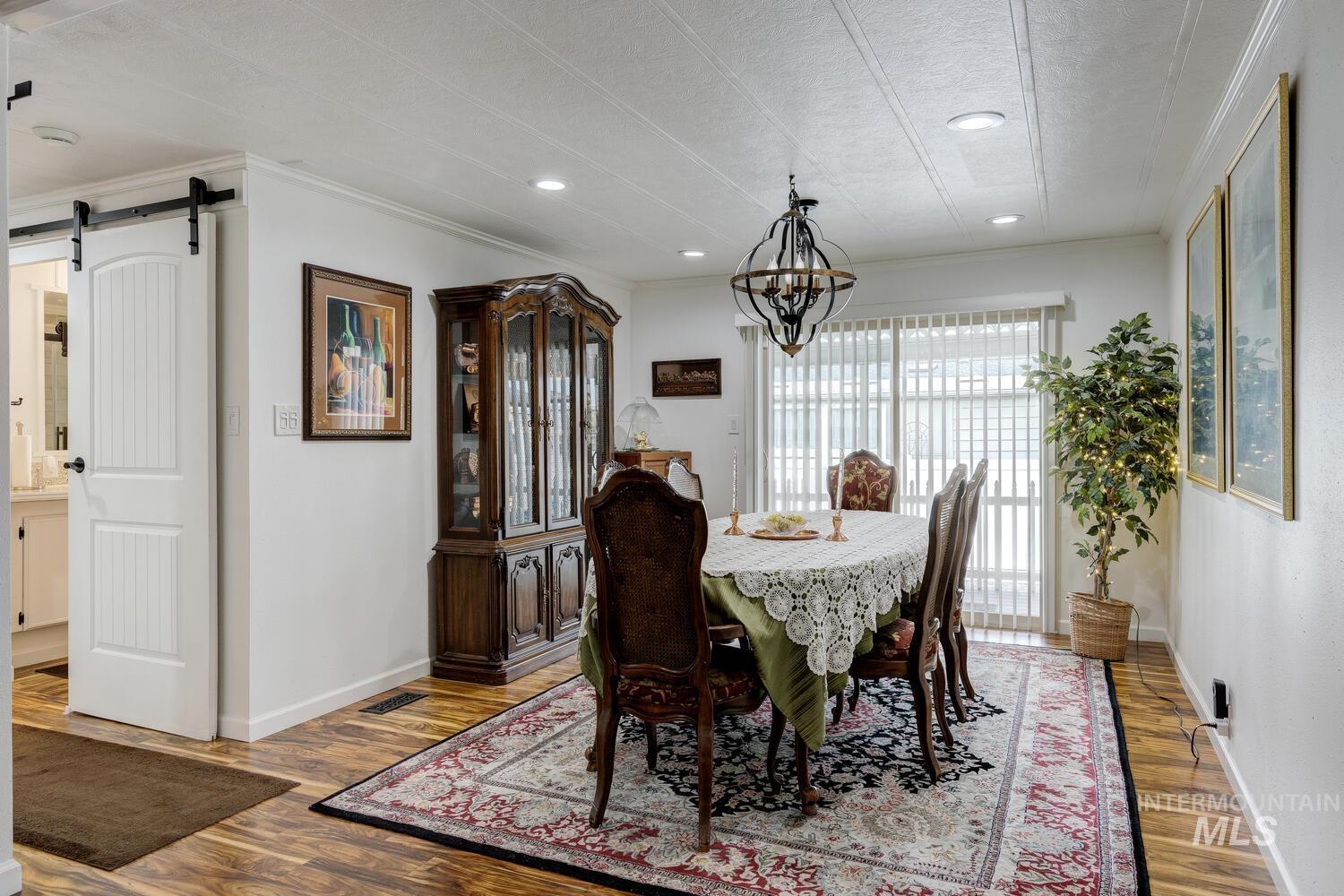 9390 West Ustick Road, Unit 64 Boise, ID 83704 - Photo 13 of 36 Dining space with a barn door, light wood-type flooring, crown molding, a chandelier, and recessed lighting