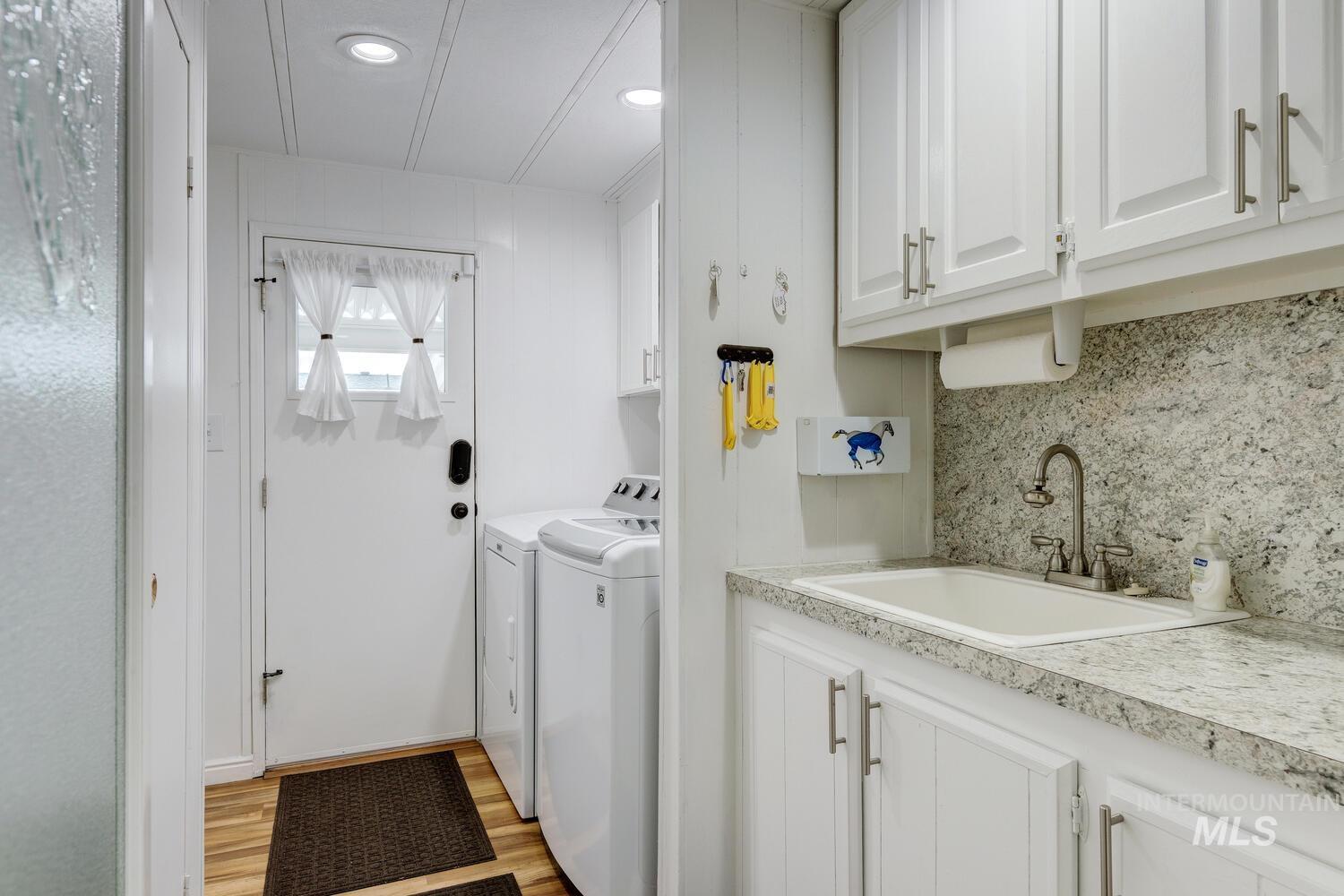 9390 West Ustick Road, Unit 64 Boise, ID 83704 - Photo 30 of 36 Washroom with independent washer and dryer, cabinet space, and light wood-style floors