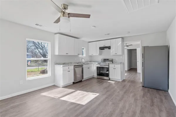 a kitchen with a white cabinets and wooden floor