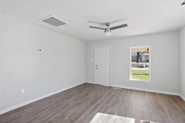 a view of an empty room with a window and wooden floor