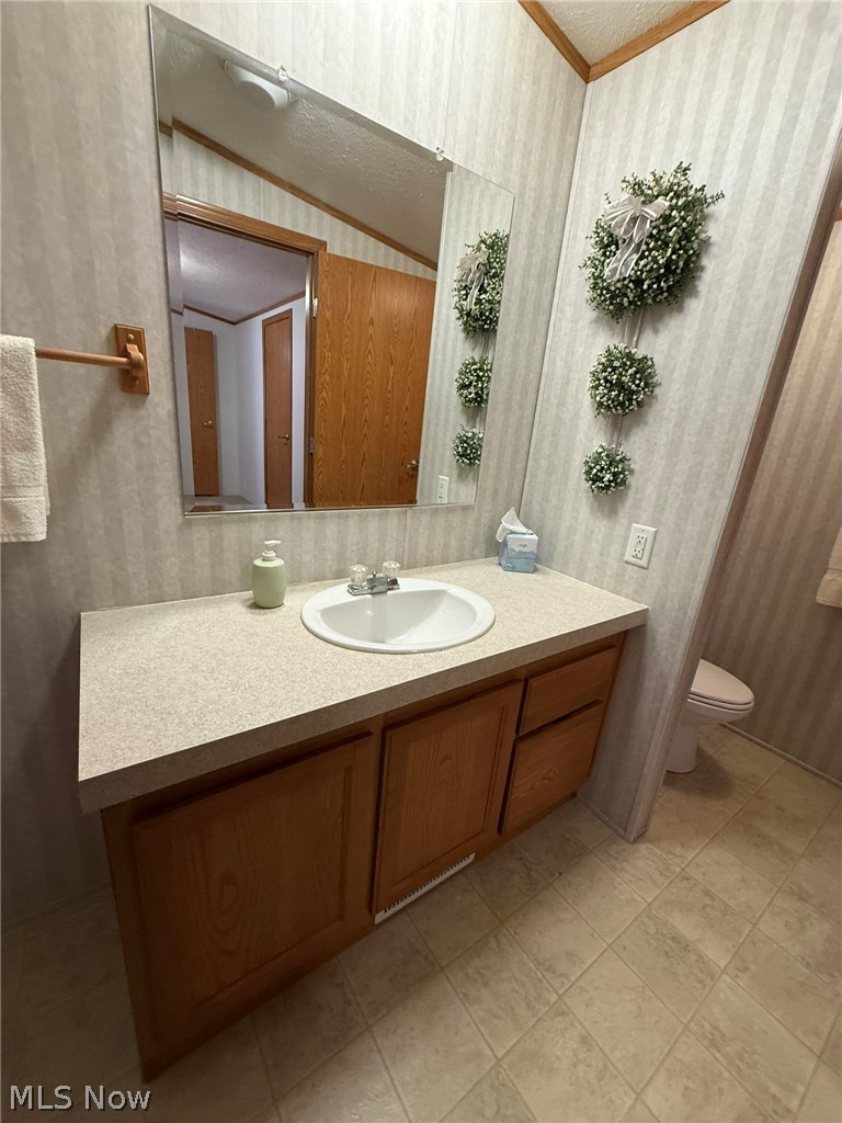 2933 Rabbit Drive Dennison, OH 44621 - Photo 18 of 28 Bathroom with wallpapered walls, vanity, and ornamental molding
