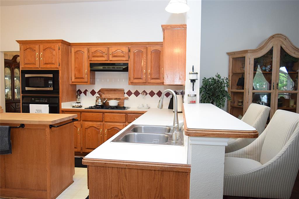 4201 Glistening Spring Rowlett, TX 75088 - Photo 7 of 33 Kitchen featuring wood cabinetry, white countertops, a double basin stainless steel sink with a high-arc faucet, and an integrated oven and microwave