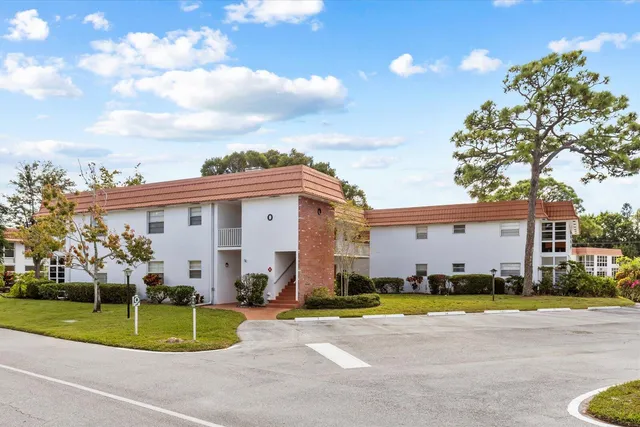 a view of a white house with a swimming pool and a yard
