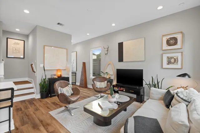 a living room with furniture floor to ceiling window and a flat screen tv
