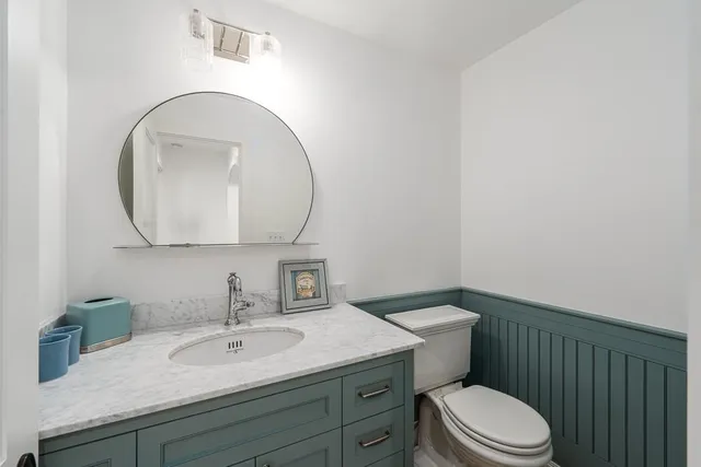 a bathroom with a granite countertop toilet a sink and mirror