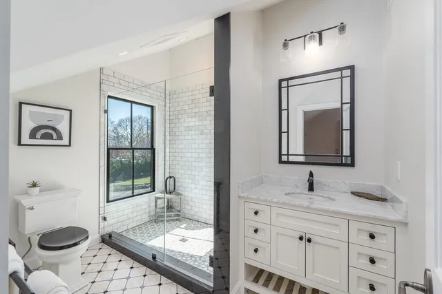 a bathroom with a granite countertop toilet sink shower and mirror