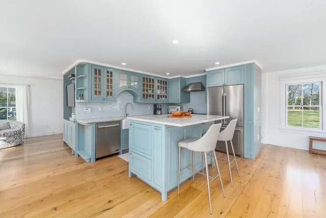 a kitchen with stainless steel appliances kitchen island granite countertop a table chairs stove and refrigerator