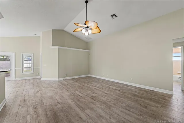 a view of an empty room with wooden floor and windows