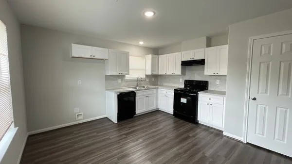 a large kitchen with a white stove top oven and white cabinets