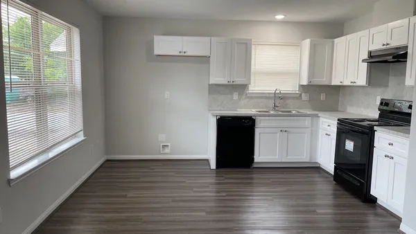 a kitchen with stainless steel appliances granite countertop a stove a sink and white cabinets