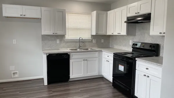 a kitchen with stainless steel appliances granite countertop a stove a sink and white cabinets